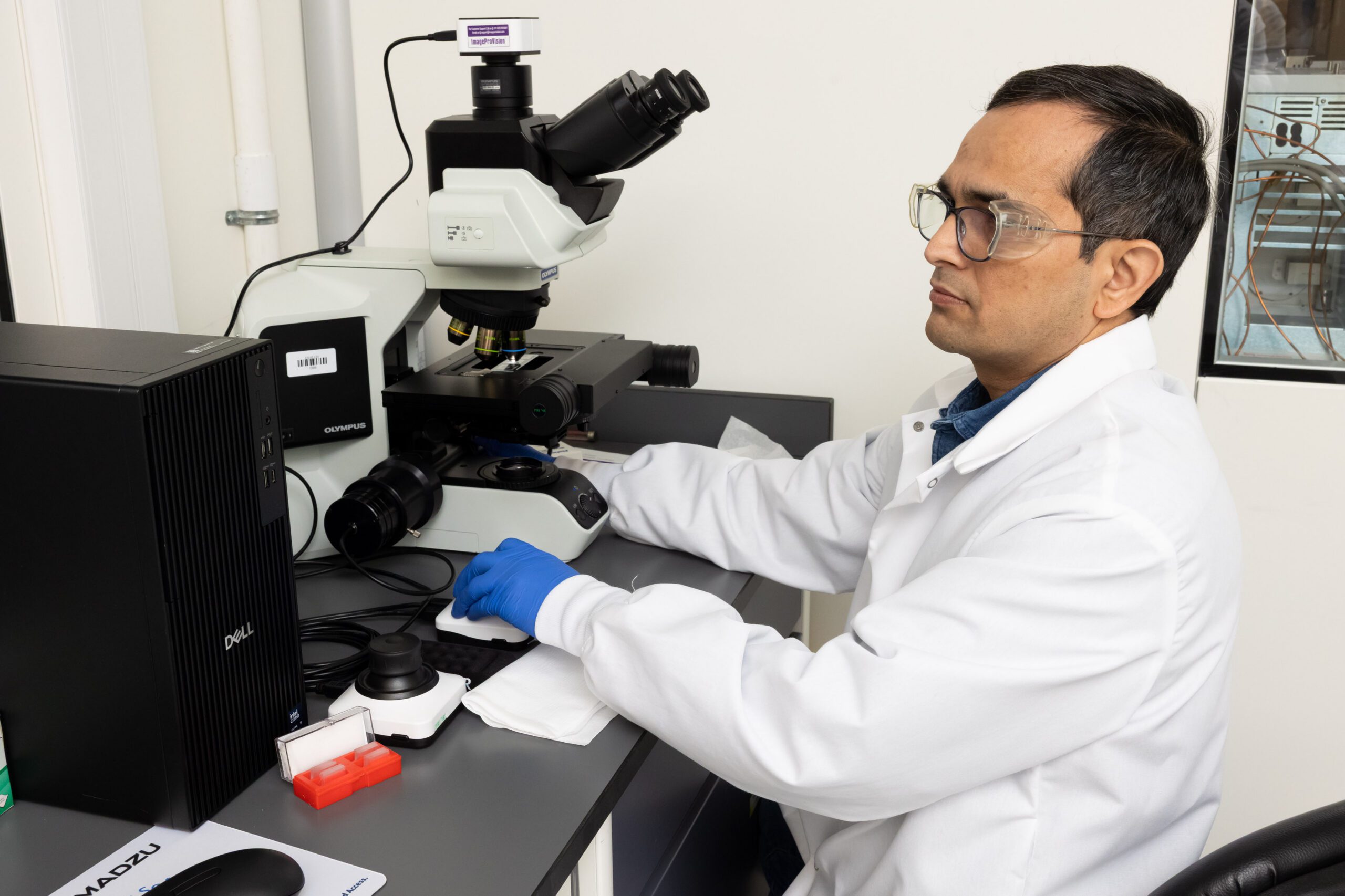 scientist conducting microscopy analysis in regulated laboratory