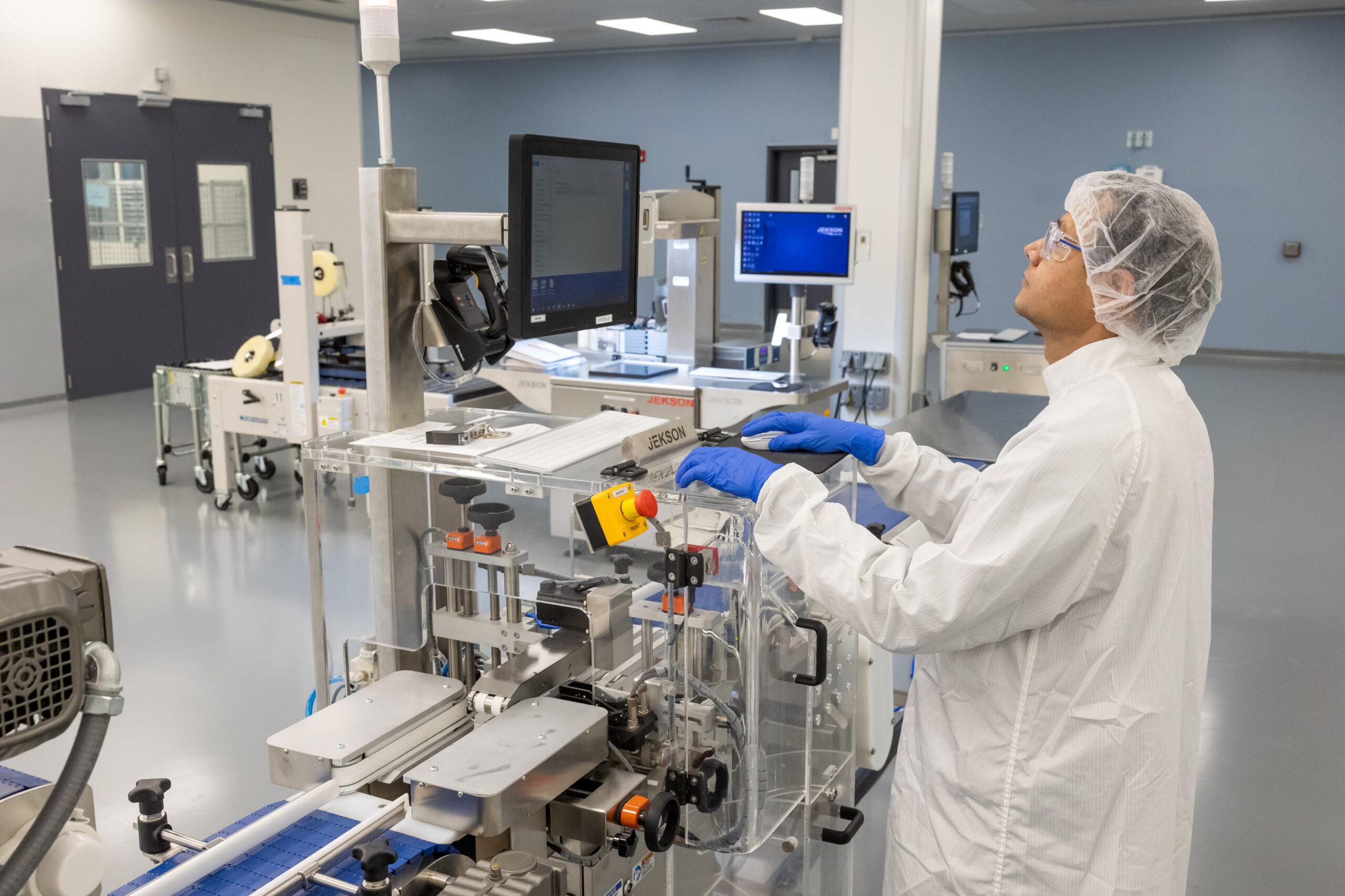 Scientist operating GMP pharmaceutical packaging and filling line for drug product distribution